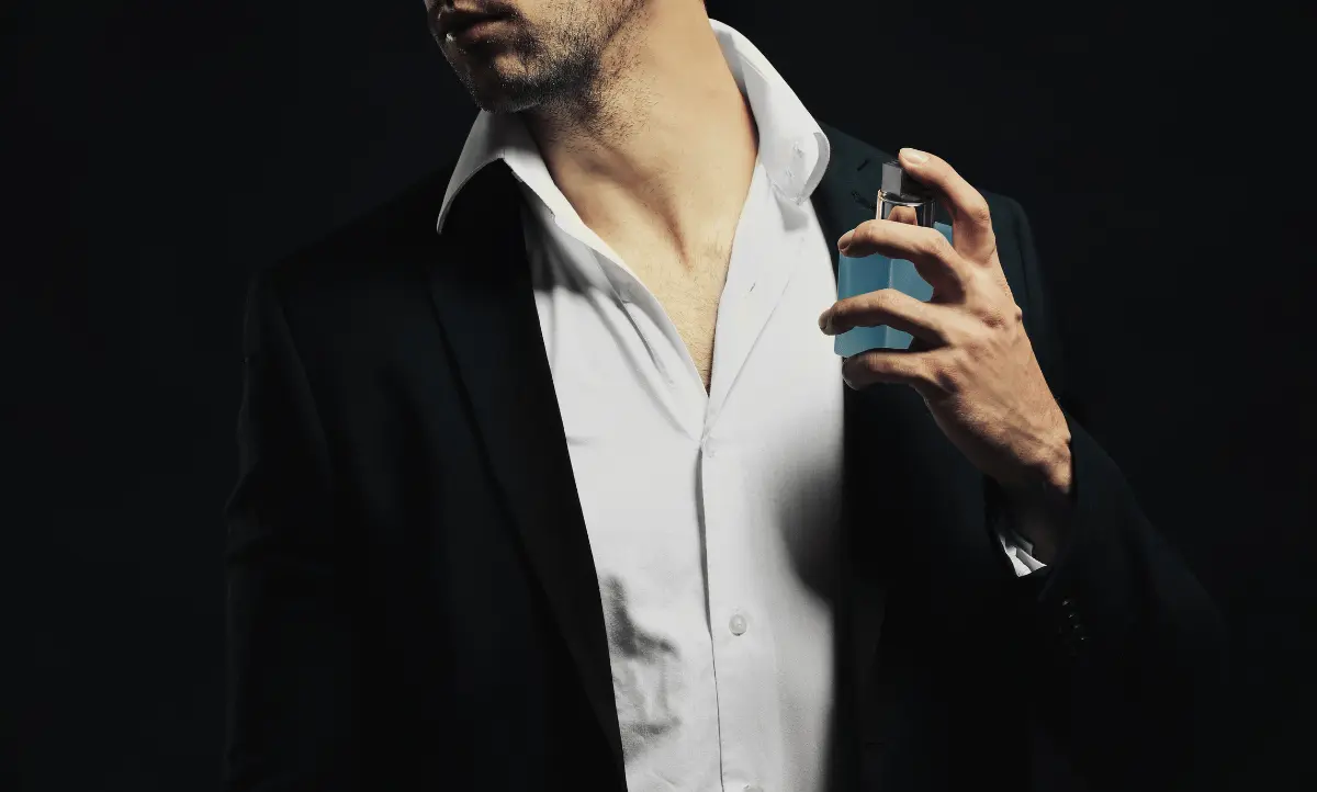 Man in een net pak die parfum aanbrengt voor een goede eerste indruk op een date.