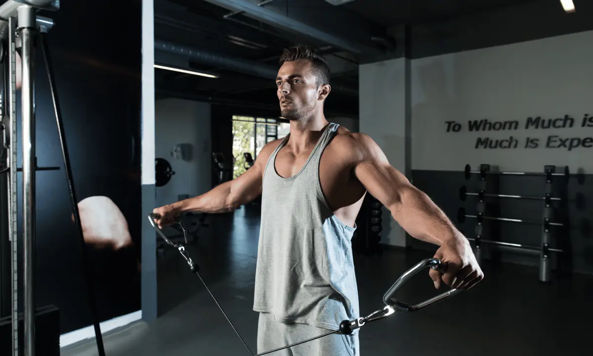 Man traint zijn schouders met een kabelmachine in de sportschool.