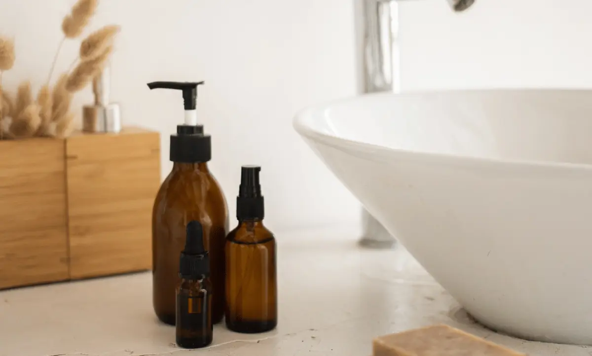 ruine flesjes met skincare-producten naast een moderne wastafel.